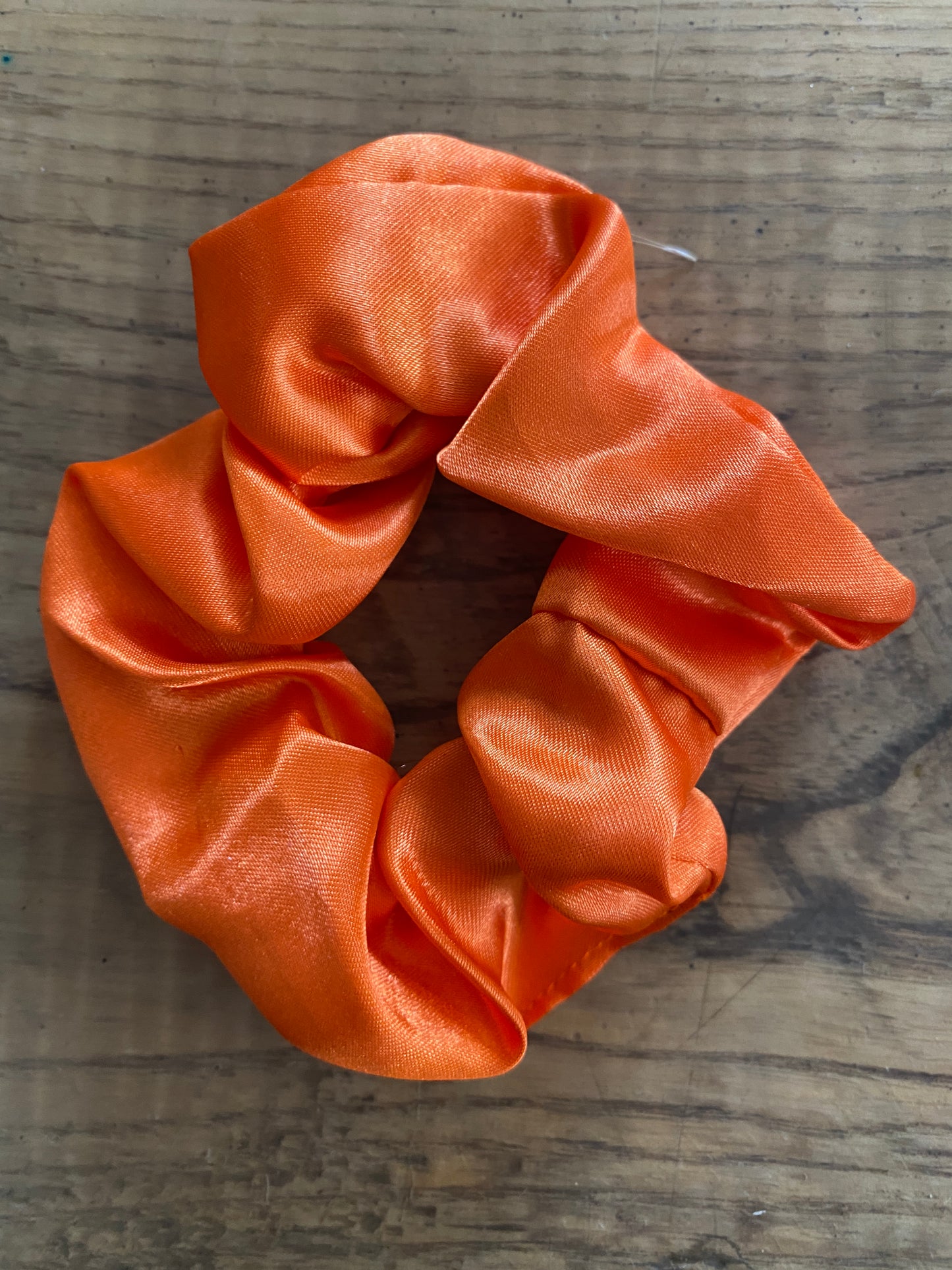 Bright orange satin scrunchy hair tie.